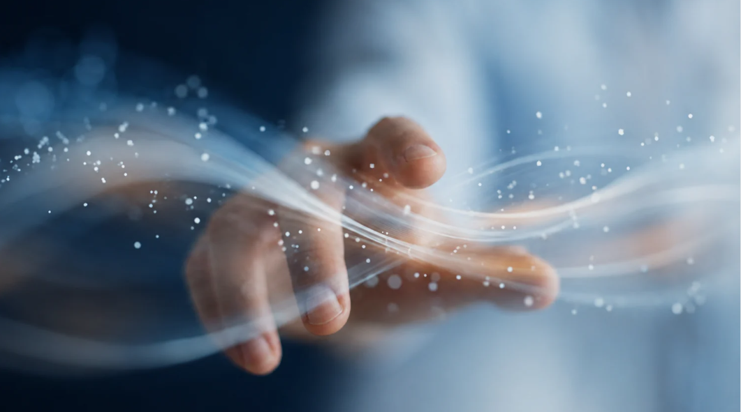 Une main traversée de flux lumineux et de particules